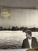 Cover jacket of Bryan Adams 'Into the Fire' vinyl record showing artist by waterfront and station compliment text