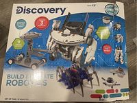 Box front showing Discovery Build & Create Robotics kit designed for ages 12+, capable of building and programming 3 robots including a spider robot with 9 designs.