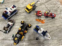 Overview of seven emergency and rescue vehicle building block toys and accessories on marble surface.
