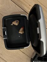 Close-up of two beige Siemens in-the-ear hearing aids inside a black and grey charging/storage case.