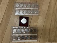 Full view of two sealed sets of Millennium quarters and one Olympic commemorative coin in a red velvet display.