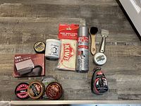 Photo showing assortment of shoe polish tins, brushes, cloth, sponge, and spray can.