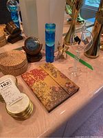 Photo showing woven coaster set, metal-edged coasters, hourglass timer, solar radiometer, and journal on a table.