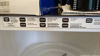 Close-up of microwave control panel label showing various settings like popcorn, potato, reheat, defrost, beverage.