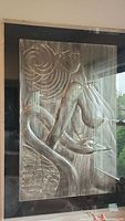 Full front view of signed metal relief sculpture in acrylic box