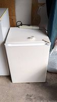 Front and top view of the white Haier mini fridge showing overall condition and power cord on top.