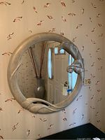 Front view of 36-inch round mirror showing textured silver sculptural frame with organic flowing shapes.