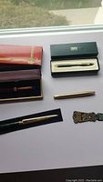 Photo shows all items including Cross pen in box, unbranded fountain pen in case, and two letter openers arranged on a white background.