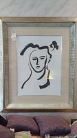 Framed abstract line art portrait of a woman with stylized black ink lines on white background and textured silver frame.