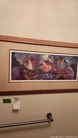 Abstract artwork featuring three figures in purples and reds, matted behind glass in a wooden frame