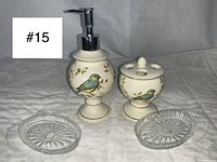 Front view of soap dispenser pump and toothbrush holder with bird designs, accompanied by two clear glass soap dishes