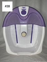 Full view of the Conair foot bath, showing white and purple basin, textured footrests, and drainage hole.