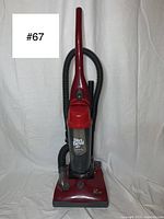 Front view of red Dirt Devil Featherlite vacuum cleaner showing upright design with hose looped behind
