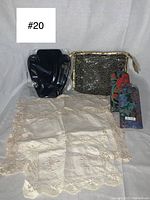 Photo showing the black velvet necklace jewelry board, two vintage floral eyeglass cases, cream doily-style handkerchiefs, and a black and gold makeup bag grouped together on white background.