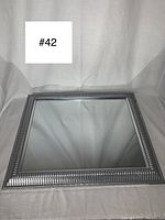 Full view of the modern square silver framed mirror showing its decorative frame and reflective surface.