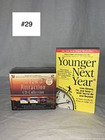 Photo of the Younger Next Year book and The Law of Attraction CD Collection box set placed on a grey surface.