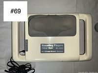 Top view of the beige portable massager showing padded kneading finger areas and brand model label.