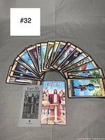 Full spread of all tarot cards fanned out along with the instruction booklet and deck box cover showing the central figure in red robe