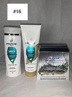 Pantene Pro-V Smooth & Sleek shampoo and conditioner bottles alongside Crest 3D WhiteStrips Charcoal Mint box on a gray background.
