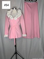 Front view of the blouse with prominent white ruffle at collar and cuffs, and palazzo pants hung beside it