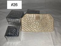 Photo showing cream beaded vintage clutch purse next to three silver-tone metal decorative storage boxes with embossed patterns.