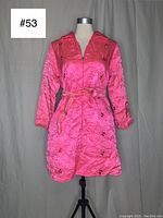 Front view of vintage neon pink 1960s mini dress on mannequin, showing floral stitching, long sleeves, collar, front zipper and matching sash belt.
