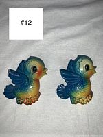 Front view of both bluebird chalkware wall plaques showing their shape, colors and details like wings and flowers.