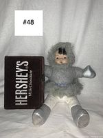 Full view of the vintage Inuit doll seated next to the Hershey's Milk Chocolate writing notebook.