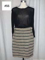 Front view of mannequin wearing black woven knit cropped shirt and checkered wool skirt.