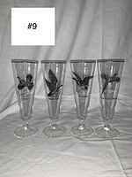 Four vintage fluted glasses with different black bird illustrations and silver rims, side by side