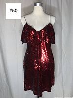 Front view of the red sequin mini dress on a mannequin showing ruffle detail and spaghetti straps.