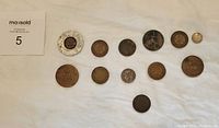 All 12 assorted antique coins laid out on white sheet, showing variety of sizes and designs.