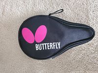 Black zippered carrying case with pink Butterfly logo on carpeted background.