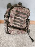 Front view of camouflage backpack showing main compartment and Molle webbing.