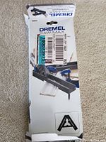 Front view of the Dremel Saw Max Crown Molding Guide in its box showing branding and product image