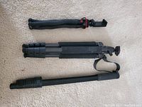 Three tripods/monopod laid out on a light carpet, showing relative size and design of each.