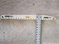 Empire T-square set on carpet, showing full T-square length with measuring scales and metal straight edge attached, highlighting the tools' condition and measurement markings.