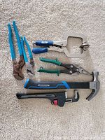 All tools in lot shown together on carpeted floor: pipe wrench, tongue and groove pliers, hammer, Kreg face clamp, small snips/shears.
