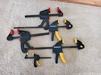 Photo showing five Mastercraft bar clamps laid on carpet, varied sizes, red and yellow pads