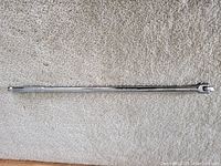 Full view of the Mastercraft long handle breaker bar, placed horizontally on carpet showing entire length and chrome finish.