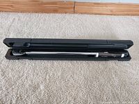 Maximum torque wrench laid in open black plastic case on carpet.