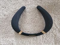 Front view of the Monster Boomerang neckband speaker showing black fabric speaker covers and gold accents on the sides.