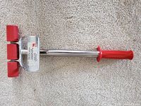 Full view of the Roberts Extendible Floor Roller showing metal frame, red segmented rollers, and red handgrip handle.