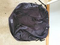 Photo showing full black SportRack rooftop cargo bag laid on carpet with straps visible