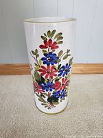 Full view of the tall cylindrical ceramic umbrella holder showing colorful floral pattern on white background.