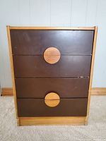 Front view of the dresser showing four dark brown drawers with large circular light wood handles.