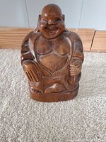 Front view of the vintage wooden laughing Buddha statue, showing detailed carving on the face, chest, and hands, with smooth polished wood grain and natural variations in color.