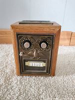 Front view of vintage wooden mailbox bank showing metal lock panel with combination dials labeled A-Z and 0-9 and number display 1157 below an eagle emblem.