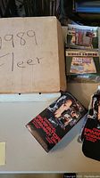 Photo showing the large cardboard box labeled '1989 Fleer' containing baseball cards and the Official Terminator Judgment Day trading card tins.