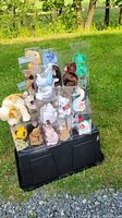 Collection of over 20 assorted Beanie Babies in clear plastic display cases arranged on a black base, outdoors on grass.